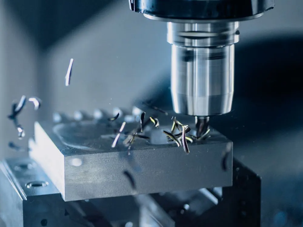 CNC freze ucu çelik bir parçayı işlerken, talaşlar havada